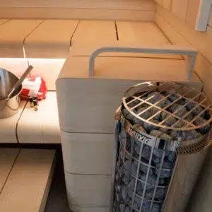 Harvia Cilindro electric sauna heater, installed beside sauna benches with metal safety guard