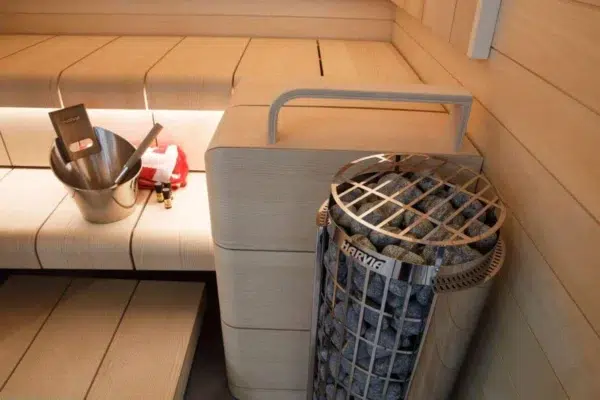 Harvia Cilindro electric sauna heater, installed beside sauna benches with metal safety guard