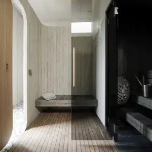HUUM DROP electric sauna heater, visible through a glass sauna wall