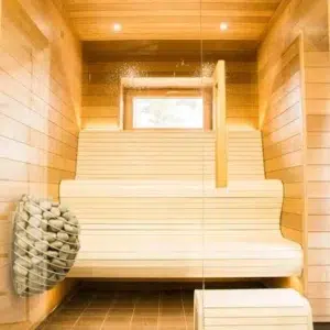 HUUM DROP electric sauna heater, wall-mounted beside pale wooden sauna benches