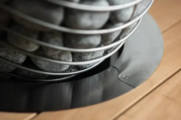 HUUM DROP embedding flange, installed around a heater in a sauna bench