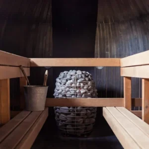 HUUM HIVE electric sauna heater, installed between sauna benches behind a wooden guard