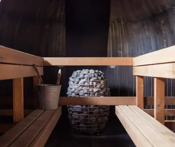 HUUM HIVE electric sauna heater, installed between sauna benches behind a wooden guard