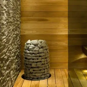 HUUM HIVE Mini electric sauna heater, installed beside a stone accent wall