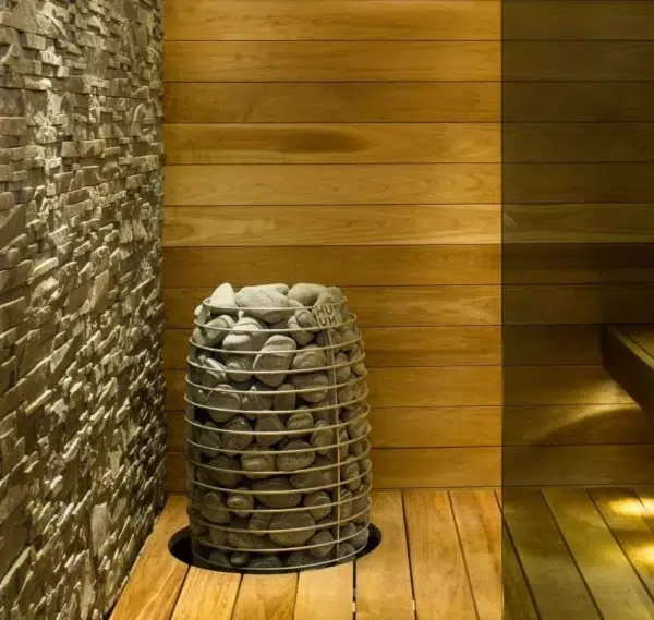 HUUM HIVE Mini electric sauna heater, installed beside a stone accent wall