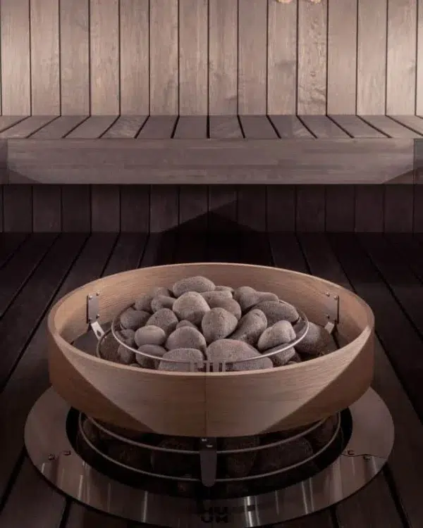 HUUM HIVE sauna heater safety railing, installed around a stone-filled heater below sauna benches