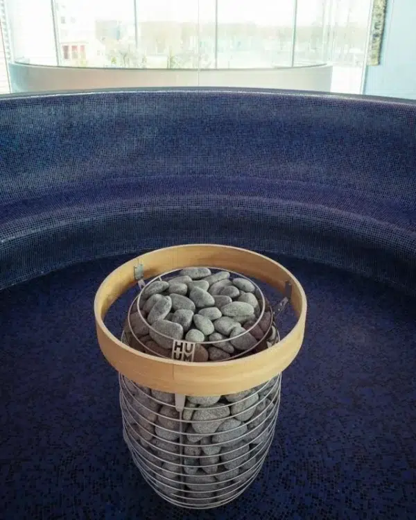 HUUM HIVE sauna heater safety railing, installed around a stone-filled heater in a sauna