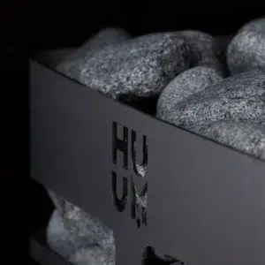 HUUM steel electric sauna heater, close view of top stones and HUUM badge
