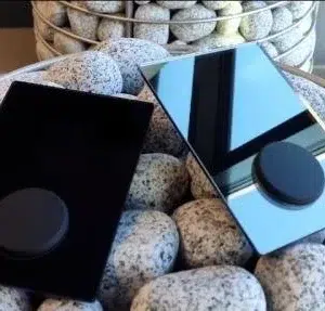 HUUM UKU sauna controls, black and mirror glass control panels resting on sauna stones
