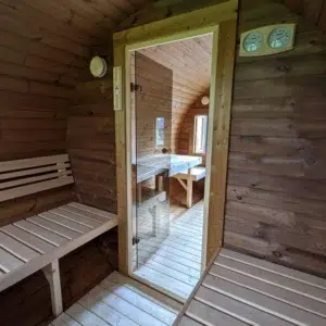 Outdoor barrel sauna, changing area with bench and glass sauna door
