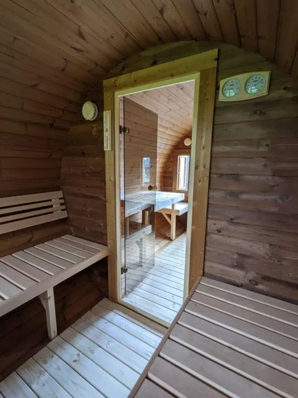 Outdoor barrel sauna, changing area with bench and glass sauna door