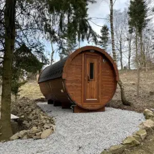 Outdoor barrel sauna, exterior on a gravel pad among trees