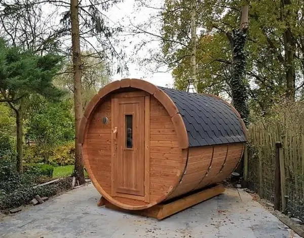 Outdoor barrel sauna, front and side exterior beside trees