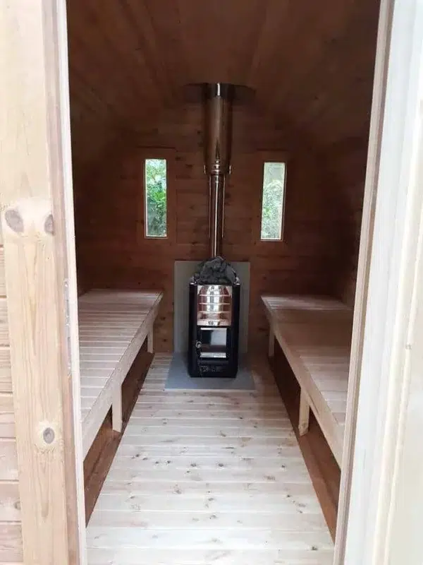 Outdoor barrel sauna, interior aisle with opposing benches and stove