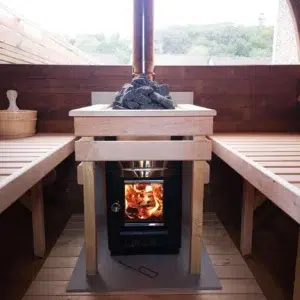 Outdoor barrel sauna, lit wood-burning stove between wooden benches