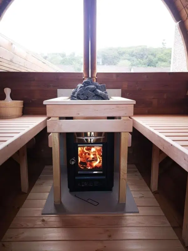 Outdoor barrel sauna, lit wood-burning stove between wooden benches