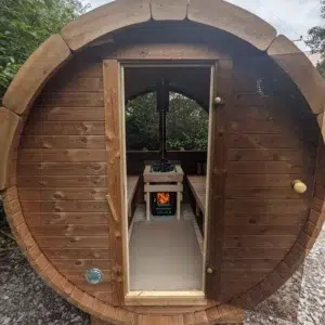 Outdoor barrel sauna, open doorway revealing the stove and benches