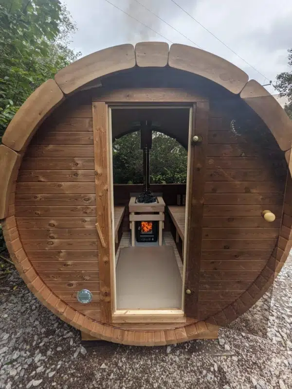 Outdoor barrel sauna, open doorway revealing the stove and benches