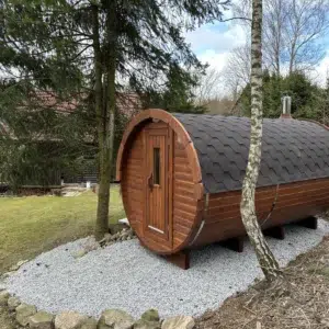 Outdoor barrel sauna, side exterior on a gravel pad among trees