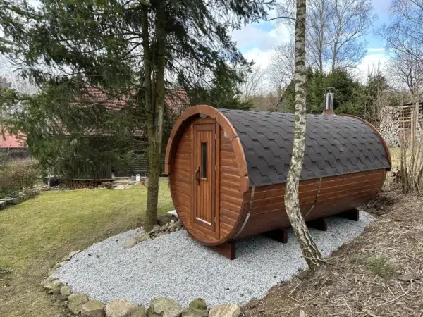 Outdoor barrel sauna, side exterior on a gravel pad among trees