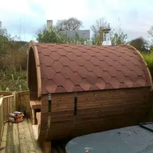 Outdoor barrel sauna, side exterior with red shingle roof