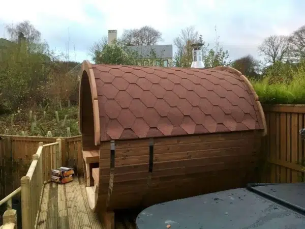 Outdoor barrel sauna, side exterior with red shingle roof