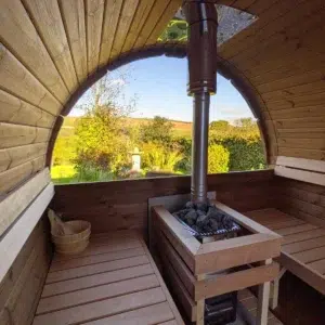 Outdoor barrel sauna, stove and benches beneath a panoramic window