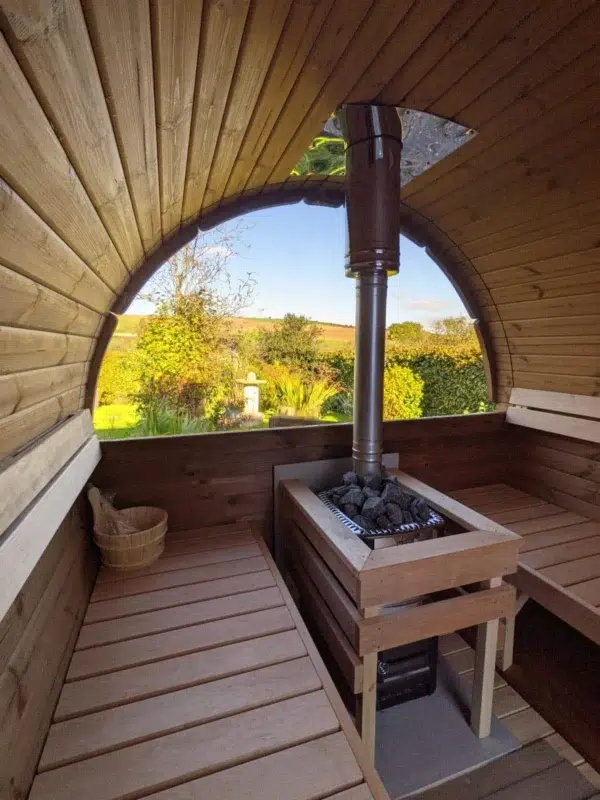 Outdoor barrel sauna, stove and benches beneath a panoramic window