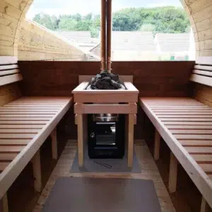 Outdoor barrel sauna, stove between wooden benches beneath a panoramic window