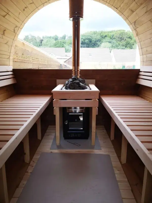 Outdoor barrel sauna, stove between wooden benches beneath a panoramic window