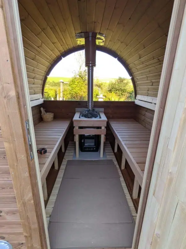 Outdoor barrel sauna, view through doorway to benches and panoramic window
