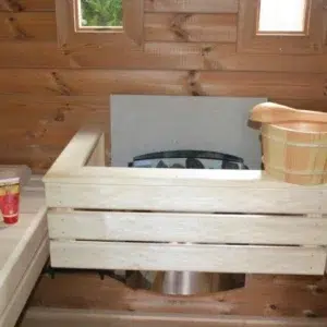 Outdoor pod sauna, close-up of heater guard and wooden bucket