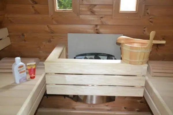 Outdoor pod sauna, close-up of heater guard and wooden bucket