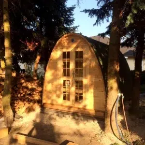 Outdoor pod sauna, front exterior beneath trees