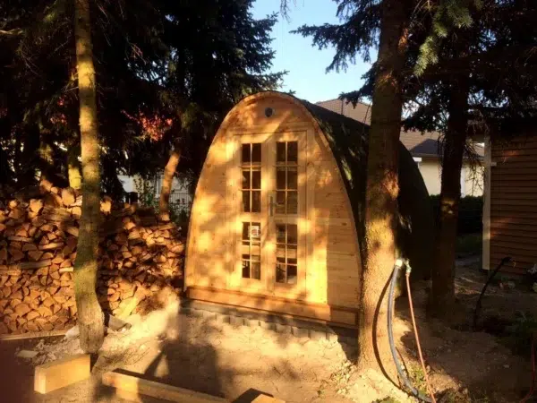 Outdoor pod sauna, front exterior beneath trees