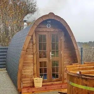 Outdoor pod sauna, front and side exterior beside a hot tub