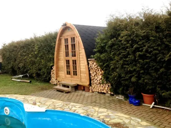 Outdoor pod sauna, garden installation beside a swimming pool