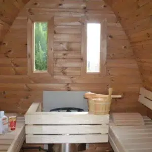 Outdoor pod sauna, interior benches around a guarded heater