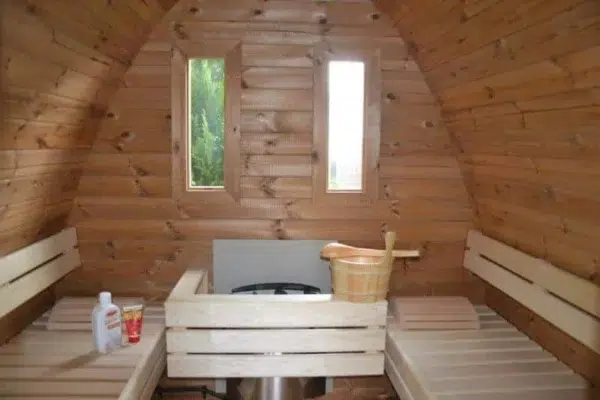 Outdoor pod sauna, interior benches around a guarded heater