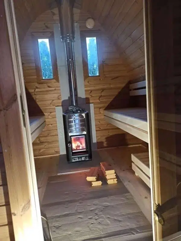 Outdoor pod sauna, interior with lit wood-burning stove
