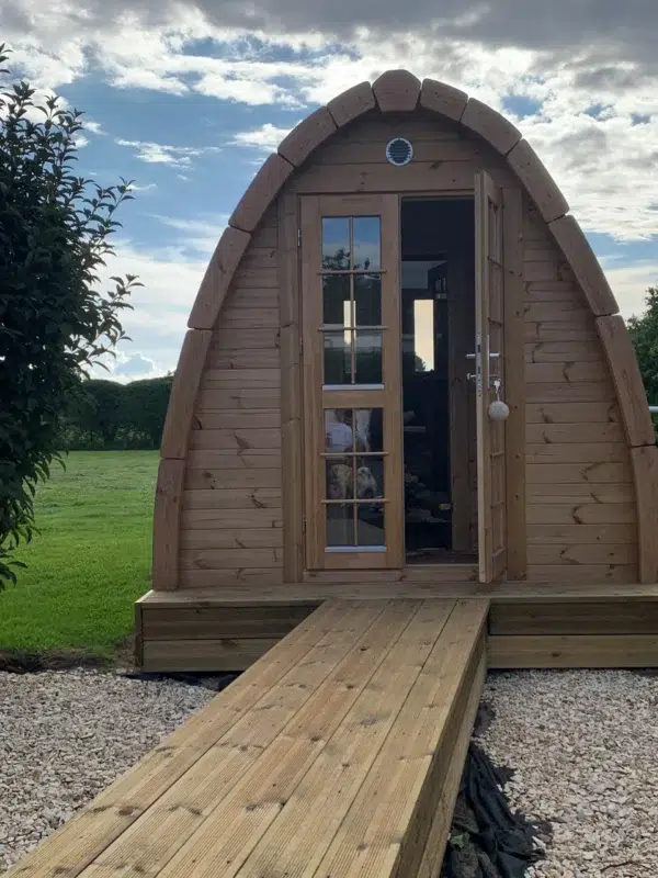 Outdoor pod sauna, open front door and wooden access ramp