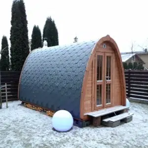 Outdoor pod sauna, side exterior in a snowy garden
