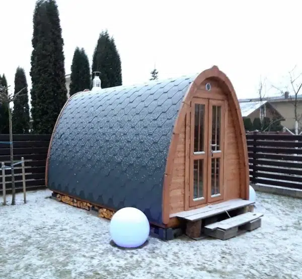 Outdoor pod sauna, side exterior in a snowy garden