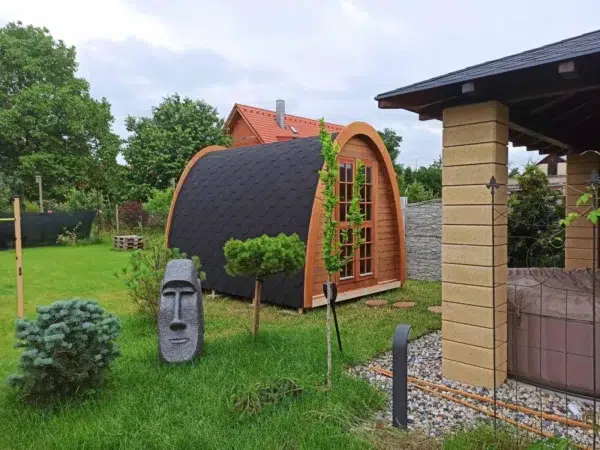 Outdoor pod sauna, side and front exterior in a garden