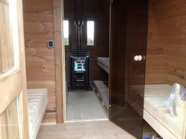 Outdoor pod sauna, view through changing area to the sauna stove