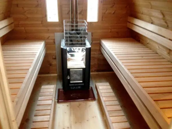 Outdoor pod sauna, wood-burning stove between opposing benches