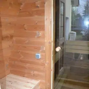 Outdoor pod sauna, wooden changing area and glass door