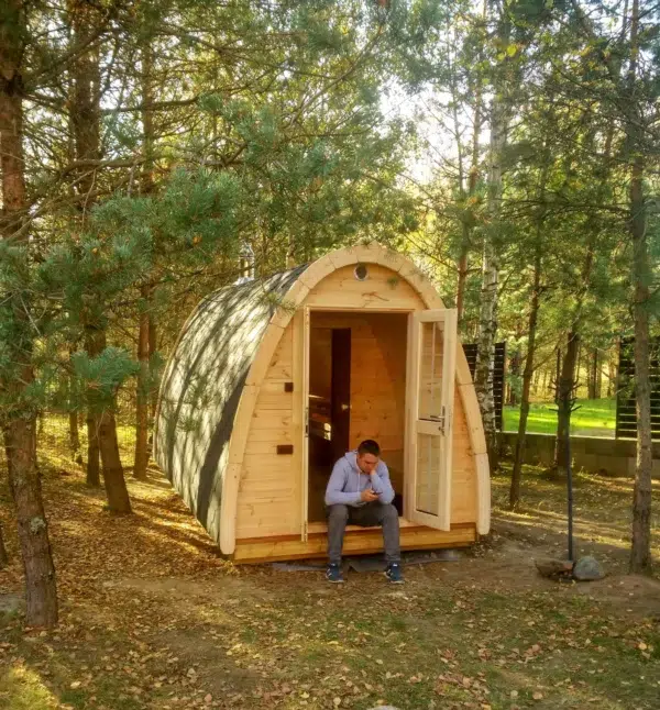 Outdoor pod sauna, woodland installation with a person at the entrance
