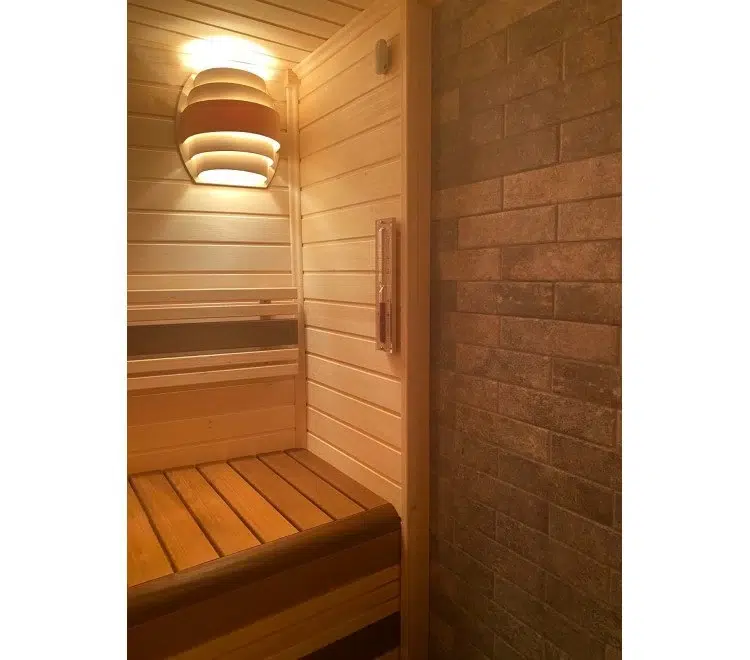 Wooden light cover glowing above a sauna bench