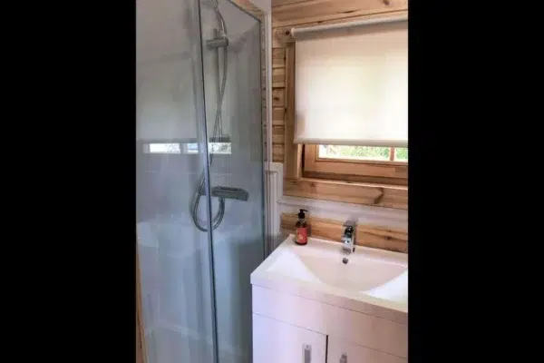 Wooden camping pod, bathroom with shower and washbasin
